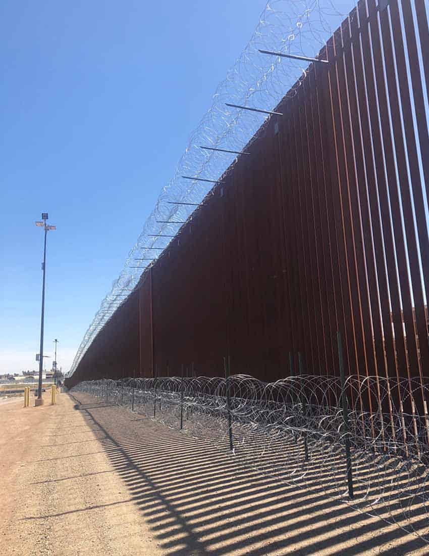 The border wall between the US and Mexico along a desert road