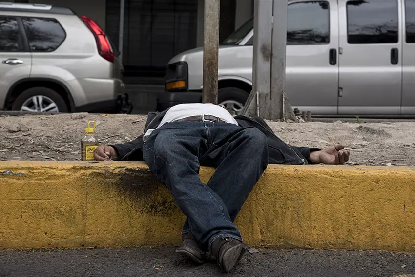 A drunk man lies on a sidewalk