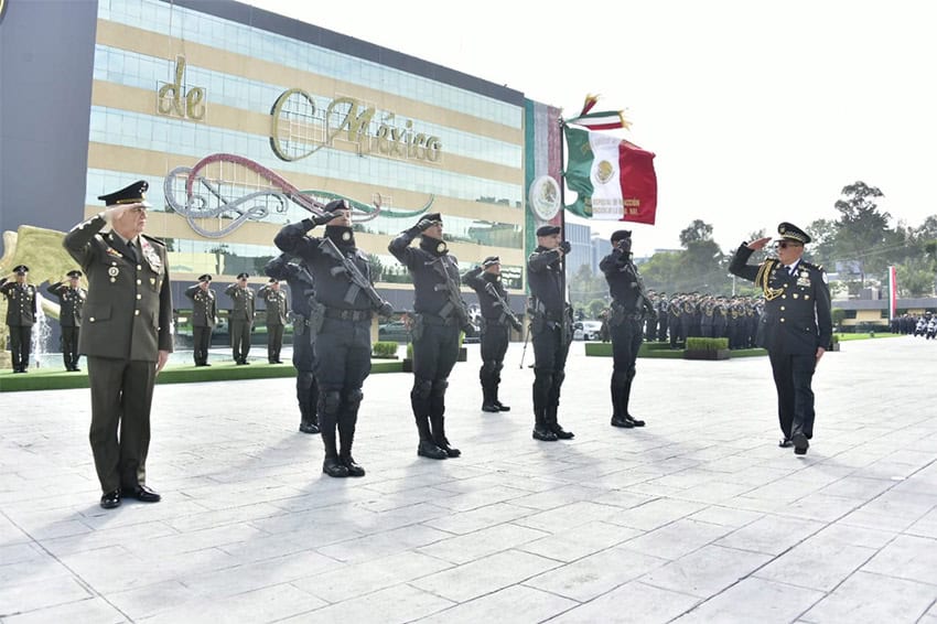 National Guard members with a Mexican flag salute a commander