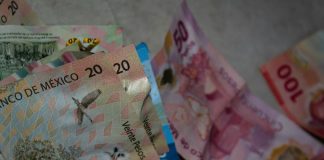 Different Mexican currency bills sitting in a chaotic pile as if thrown on a table