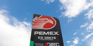 A Pemex gas station sign against a blue sky dotted with clouds