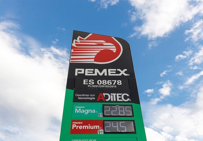 A Pemex gas station sign against a blue sky dotted with clouds