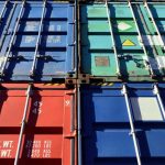 Four shipping containers in various shades of red and blue piled atop each other