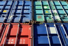 Four shipping containers in various shades of red and blue piled atop each other