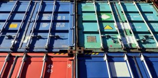 Four shipping containers in various shades of red and blue piled atop each other
