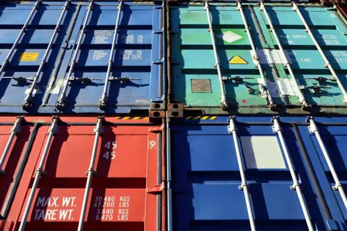 Four shipping containers in various shades of red and blue piled atop each other