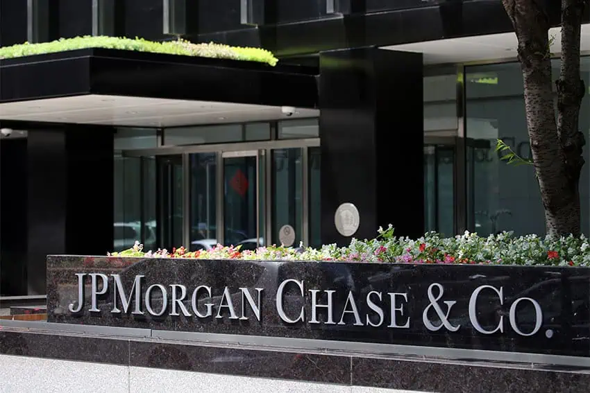 Front entrance to JP Morgan building in New York City, with embossed lettering near the doors saying JP Morgan Chase & Co. and flowers growing behind the sign