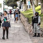 Young women walk down a sidewalk while a member of the National Guard stands guard, illustrating the level of perceived insecurity in Mexican cities