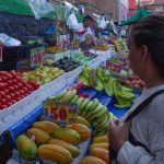 A woman looks at fruit and vegetables in a Mexican market, with the prices marked