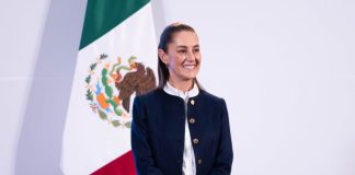 President Claudia Sheinbaum stands with a Mexican flag