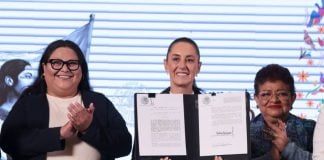 President Claudia Sheinbaum holds up a signed copy of the Mexican women's rights amendment