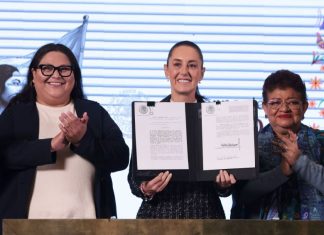 President Claudia Sheinbaum holds up a signed copy of the Mexican women's rights amendment