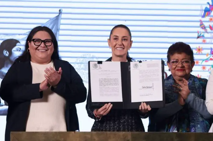 President Claudia Sheinbaum holds up a signed copy of the Mexican women's rights amendment