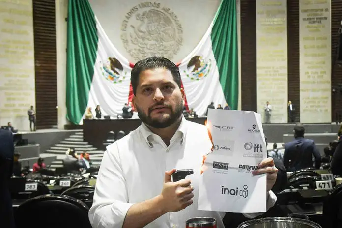 PRI deputy Carlos Eduardo Gutiérrez burns a piece of paper with the names of the INAI and other Mexican watchdog agencies, in Mexico's Senate chambers