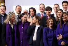 Mexico's President Sheinbaum at the center of a group of CEOs and business leaders at the presidential podium in the National Palace.