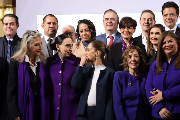 Mexico's President Sheinbaum at the center of a group of CEOs and business leaders at the presidential podium in the National Palace.