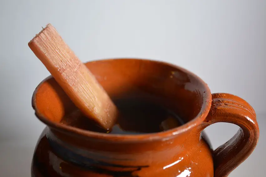 Traditional jug (jarrito) with ponche navideño (Mexican Christmas punch). It have fruits inside as tamarind, apple, guava, hibiscus flowers, tejocote, and was made with cinnamon and piloncillo (unrefined cane sugar). It's commonly served with a cane thin strip as the photo shows.