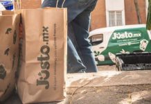 A delivery person from Mexican company Jüsto holds a pair of paper bags