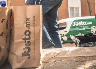 A delivery person from Mexican company Jüsto holds a pair of paper bags