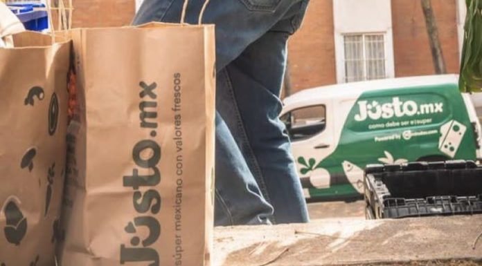 A delivery person from Mexican company Jüsto holds a pair of paper bags