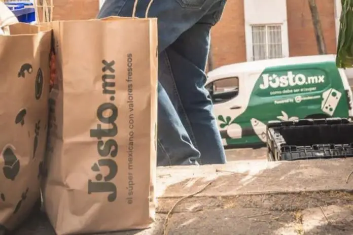 A delivery person from Mexican company Jüsto holds a pair of paper bags