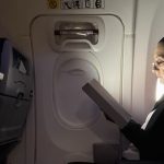 Mexico's President Claudia Sheinbaum sitting in a commercial flight looking at an e-reader as she heads from Mexico to the 2024 G20 Leaders' Summit