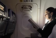 Mexico's President Claudia Sheinbaum sitting in a commercial flight looking at an e-reader as she heads from Mexico to the 2024 G20 Leaders' Summit