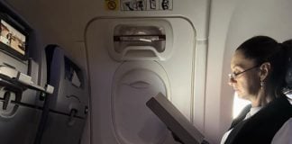 Mexico's President Claudia Sheinbaum sitting in a commercial flight looking at an e-reader as she heads from Mexico to the 2024 G20 Leaders' Summit