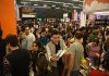 A crowd holds books and moves around a large indoor space at the Guadalajara International Book Fair