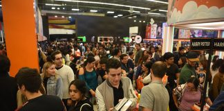 A crowd holds books and moves around a large indoor space at the Guadalajara International Book Fair