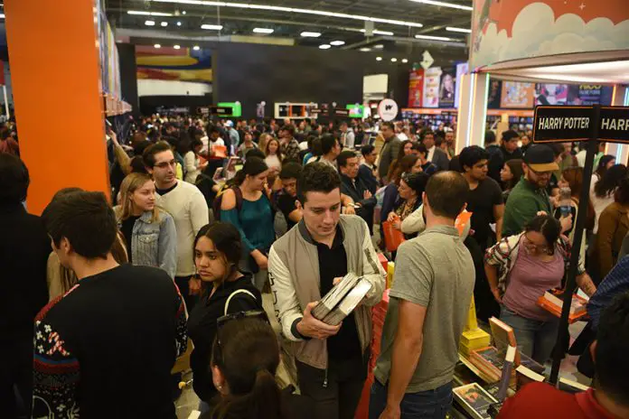 A crowd holds books and moves around a large indoor space at the Guadalajara International Book Fair