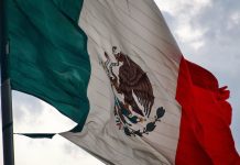 A close-up of a tattered Mexico flag waving in the sky