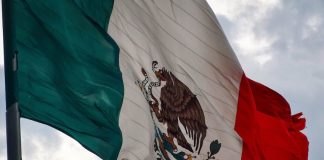 A close-up of a tattered Mexico flag waving in the sky