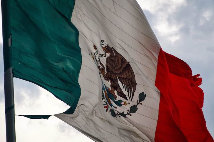 A close-up of a tattered Mexico flag waving in the sky