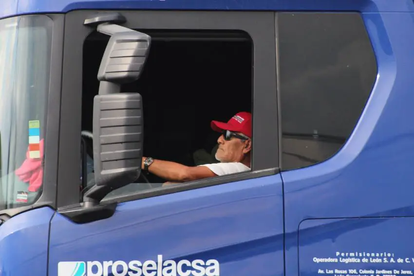 Side view of a truck driver seated in his blue tractor trailer