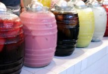 Row of jugs of different-colored aguas frescas