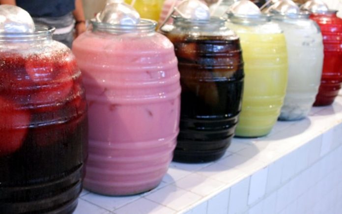 Row of jugs of different-colored aguas frescas