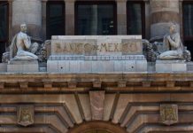 The top of the facade of the Bank of Mexico building in Mexico City, which features a sculptured man and woman in ancient Roman-style dress on either side of a block of stone saying Banco de Mexico