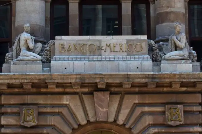 The top of the facade of the Bank of Mexico building in Mexico City, which features a sculptured man and woman in ancient Roman-style dress on either side of a block of stone saying Banco de Mexico