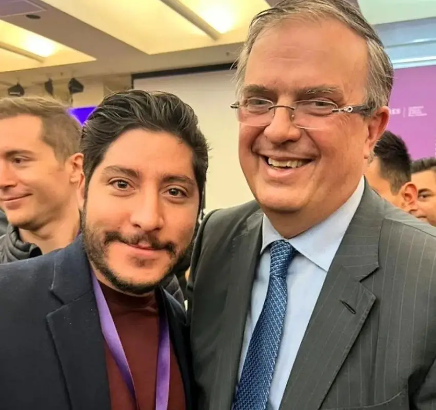 Yumari CEO Andres Diaz Bedolla posing for a selfie at an event with Mexico's Economy Minister Marcelo Ebrard. Both are smiling and are surrounded by people at the event.