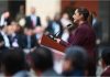 Claudia Sheinbaum at a podium addressing a crowd of Mexican legislators in Mexico's National Palace