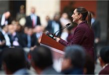 Claudia Sheinbaum at a podium addressing a crowd of Mexican legislators in Mexico's National Palace