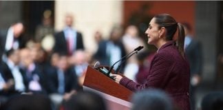 Claudia Sheinbaum at a podium addressing a crowd of Mexican legislators in Mexico's National Palace