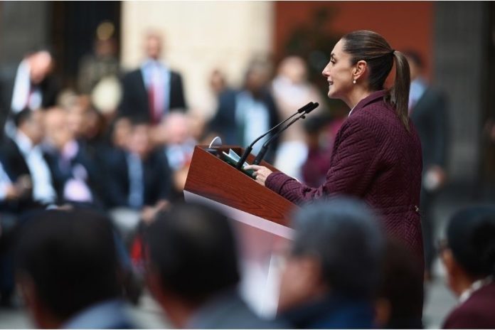 Claudia Sheinbaum at a podium addressing a crowd of Mexican legislators in Mexico's National Palace