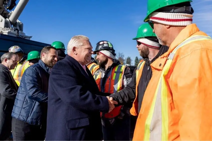 Ontario premier Doug Ford shaking the hand of a worker in an orange hazard and hardhat at a Canadian training facility site for crane operators.