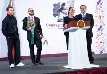 Boxer Canelo Álvarez appears on stage with his manage, who wears sunglasses and carries Álvarez wrestling