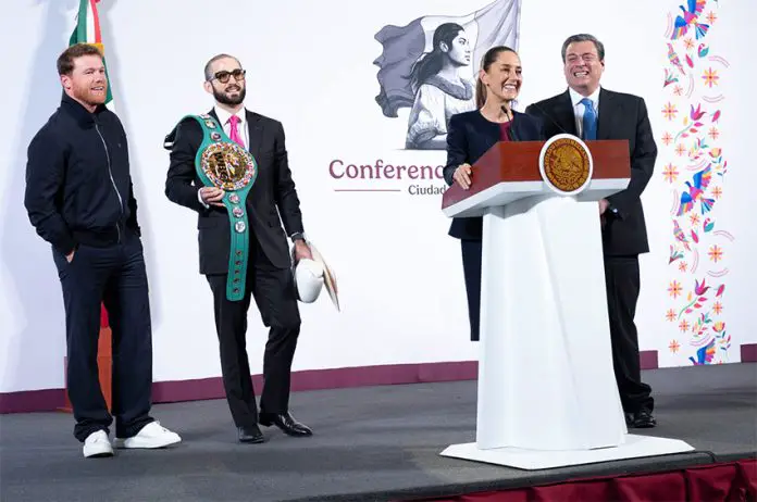 Boxer Canelo Álvarez appears on stage with his manage, who wears sunglasses and carries Álvarez wrestling