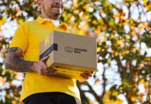 A delivery person in a yellow shirt holds a brown package with the Mercado Libre logo