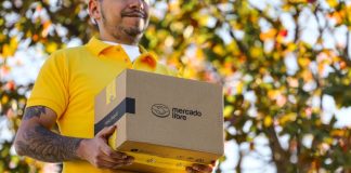 A delivery person in a yellow shirt holds a brown package with the Mercado Libre logo