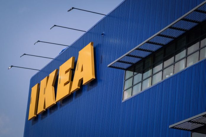 Front of an IKEA store, a blue corrugated metal facade with the yellow IKEA logo's letters in all caps in the top left of the photo.